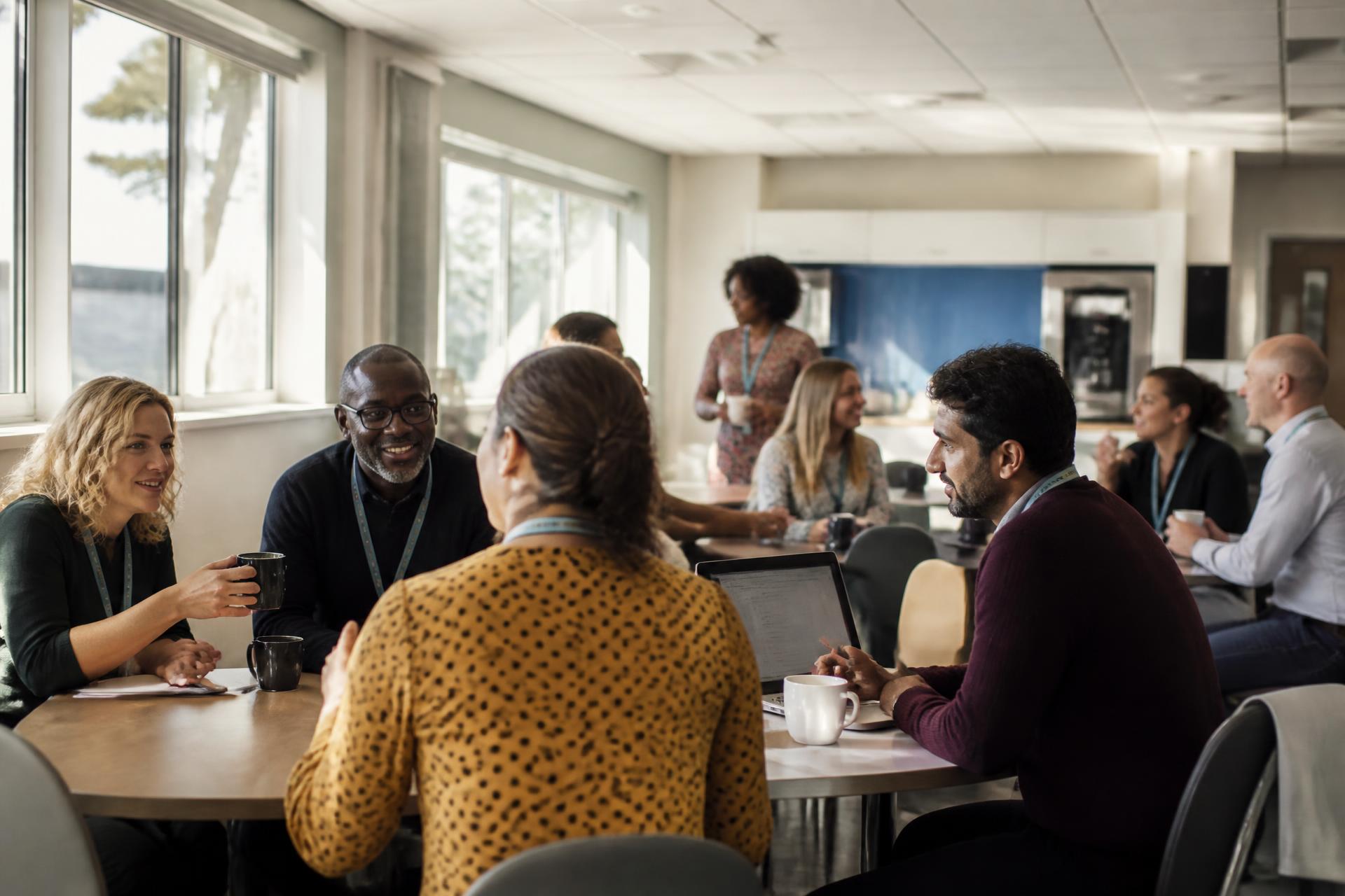 Educators mid-conversation in a bright school staffroom